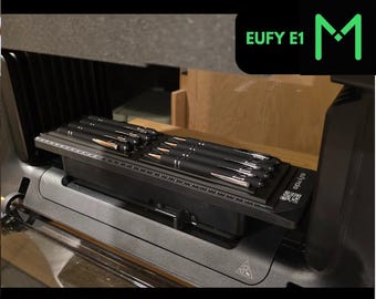 Könnte beinhalten: Eine schwarze Stiftvorrichtung mit mehreren geladenen Stiften, die für UV-Drucker konzipiert ist. Das Bild enthält den Text "PEN JIG" und "FOR UV PRINTERS" in Grün. Das Produkt ist mit "EUFY E1" und einem grünen "M"-Logo gekennzeichnet.