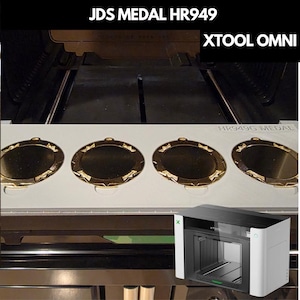 May include: Four gold-colored circular medals with decorative edges are arranged in a row on a white rectangular tray inside an XTOOL OMNI laser machine. The text JDS MEDAL HR949 and XTOOL OMNI is visible at the top, with HR949G MEDAL on the tray.
