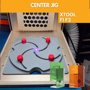 May include: A gray center jig for xTool F1 F2 laser machines featuring four red cylindrical pins positioned within curved slots on a square base. The text CENTER JIG and XTOOL F1 F2 is visible at the top. A small purple laser dot is centered.