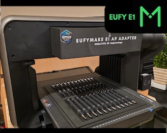 May include: A black and silver UV printer with a pen jig attachment. The jig holds multiple pens in place for engraving. The printer has a black and white display screen and a black and white label that reads "EUFYMAKE E1 AP ADAPTER CREATIVE 3D Engravings".