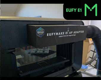 May include: A black 3D printer with a black and gray air purifier adapter attached to the top. The adapter has a label that reads "EUFYMAKE E1 AP ADAPTER CREATIVE 3D Engravinga". The printer is labeled "EUFY E1".