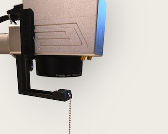 May include: A silver and black laser alignment device with a chain attached to the bottom. The device is labeled "F-theta lens 355nm". The text "ATTACH TO MOST FIBER LASERS IN SECONDS" is at the bottom of the image.