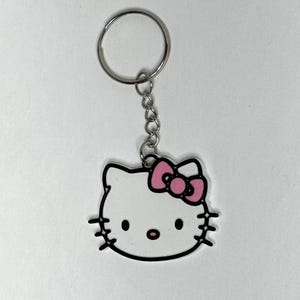 May include: A white Hello Kitty keychain with a pink bow and a silver chain and ring.