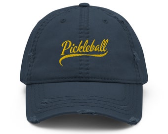Puede incluir: Una gorra de béisbol azul marino desgastada con la palabra "Pickleball" bordada en amarillo.