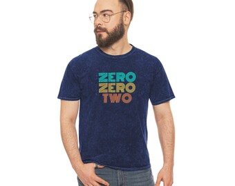 May include: A dark blue t-shirt with a vintage-style graphic that reads "ZERO ZERO TWO" in yellow, orange, and turquoise.