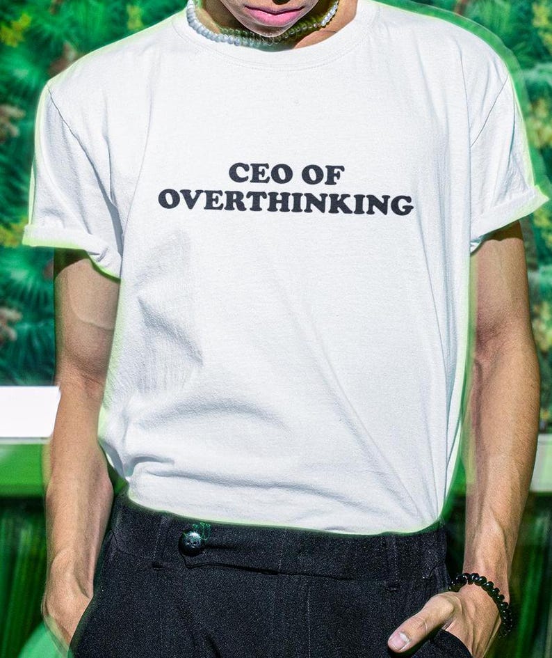 May include: White t-shirt with black text that reads "CEO OF OVERTHINKING".