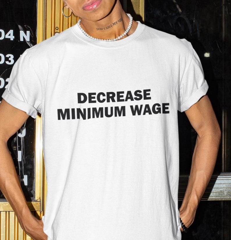 May include: White t-shirt with the text "DECREASE MINIMUM WAGE" printed in black.