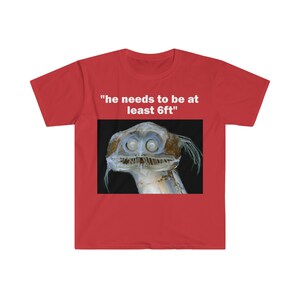 Puede incluir: Camiseta roja con un gr&aacute;fico blanco de una criatura de aguas profundas con el texto "tiene que medir al menos 6 pies"