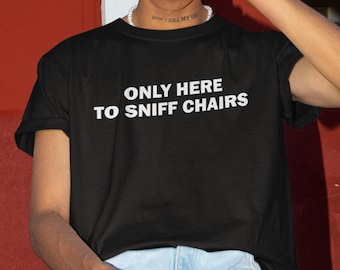 Pode incluir: Camiseta preta com texto branco que diz "Only here to sniff chairs."
