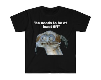 Puede incluir: Camiseta negra con un gráfico blanco de una criatura de aguas profundas con el texto "he needs to be at least 6ft" impreso en ella.