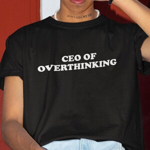 May include: Black t-shirt with white text that reads "CEO of Overthinking".