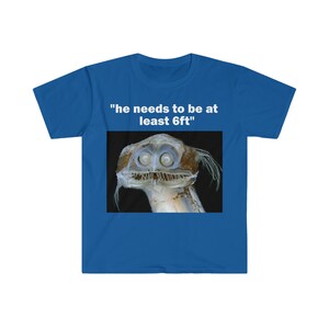 Puede incluir: Camiseta azul con el texto "he needs to be at least 6ft" y una imagen de una criatura de aguas profundas con ojos grandes.
