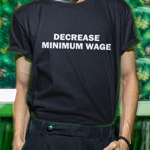 May include: A black t-shirt with the text "DECREASE MINIMUM WAGE" printed in white.