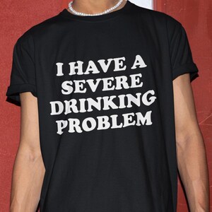 Może przedstawiać: Czarny T-shirt z białym napisem "Mam poważny problem z alkoholem".