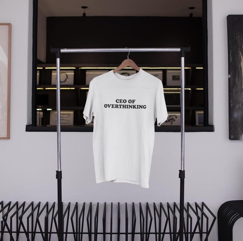 May include: White t-shirt with the text "CEO of Overthinking" printed in black on the front.