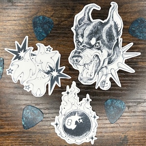 May include: A set of three ceramic mugs with a speckled, matte finish in cream, light grey, and dark grey. Each mug has a simple, minimalist design and a rounded handle. The mugs are stacked on top of each other.