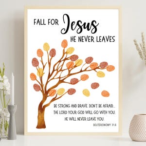 Puede incluir: Una impresión enmarcada con las palabras "FALL FOR Jesus HE NEVER LEAVES" en escritura negra. Se presenta un árbol de acuarela con formas de hojas naranjas, amarillas y marrones. La impresión incluye un versículo bíblico.