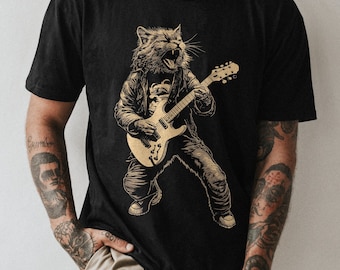 May include: A black t-shirt featuring a graphic of a cat playing an electric guitar. The cat is wearing a leather jacket and has a fierce expression on its face.