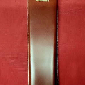 May include: A brown leather case with the word "PICKETT" embossed in gold lettering.