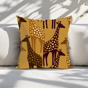 May include: Square throw pillow with a repeating pattern of giraffes in shades of brown and gold. The giraffes have dark brown spots and are set against a mustard yellow background. The pillow is on a white surface.