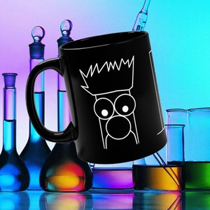 May include: Black ceramic coffee mug with a white graphic of a cartoon character with a crown, large eyes, and a round nose. The mug is surrounded by colorful glass bottles.