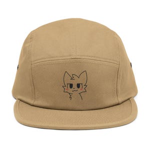 Könnte beinhalten: Eine beigefarbene 5-Panel-Baseballkappe mit einem schwarzen gestickten Cartoon-Katzenkopf auf der Vorderseite.