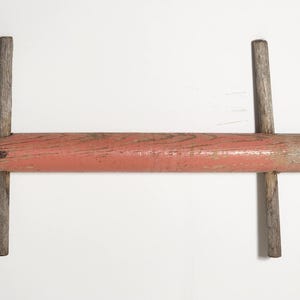 May include: A wooden rolling pin with two cross pieces, painted red.