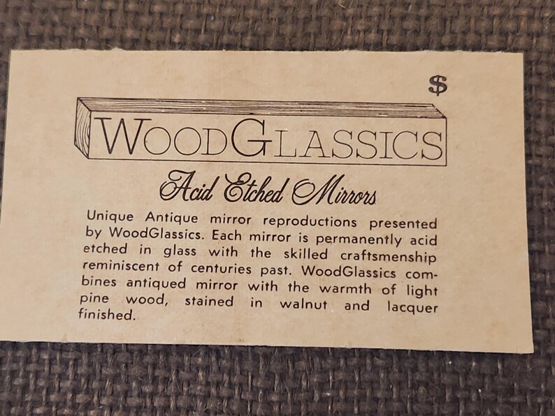 Puede incluir: Una tarjeta de visita rectangular de color beige con el texto WoodGlassics Acid Etched Mirrors. El logotipo muestra una viga de madera sobre el nombre de la marca. El texto describe reproducciones de espejos con vidrio grabado al &aacute;cido y pino te&ntilde;ido de nogal.