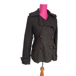 May include: A dark brown double-breasted pea coat with a notched collar and two front pockets. The coat has dark brown buttons and a tailored fit. The coat is displayed on a mannequin.