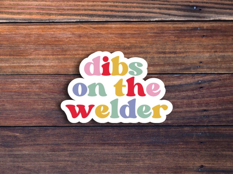 May include: A colorful sticker with the text "dibs on the welder" in a white border. The words are in different colors, including pink, yellow, blue, green, and red.