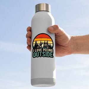 May include: A white stainless steel water bottle with a retro-style sticker featuring a mountain landscape and the text "I LOVE PEEING OUTSIDE".