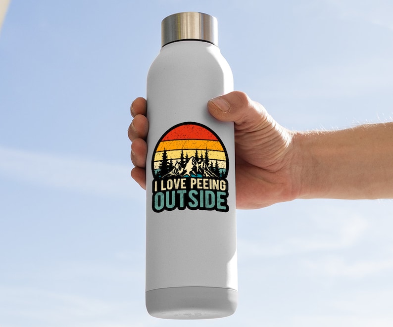 May include: A white stainless steel water bottle with a retro-style sticker featuring a mountain landscape and the text "I LOVE PEEING OUTSIDE".