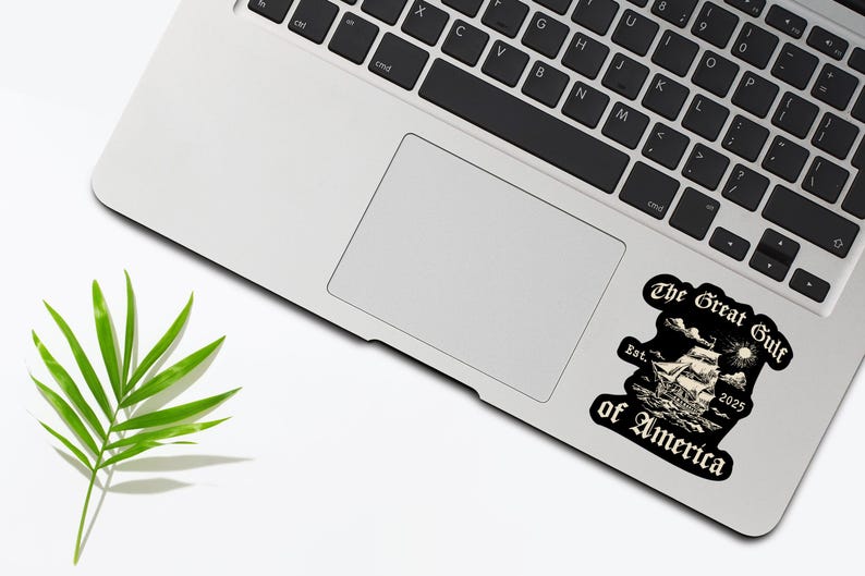 May include: A black and white sticker with a vintage illustration of a ship sailing on the water. The text "The Great Gulf of America" is written in a gothic font with the year "2025" and the word "Est." below the ship.