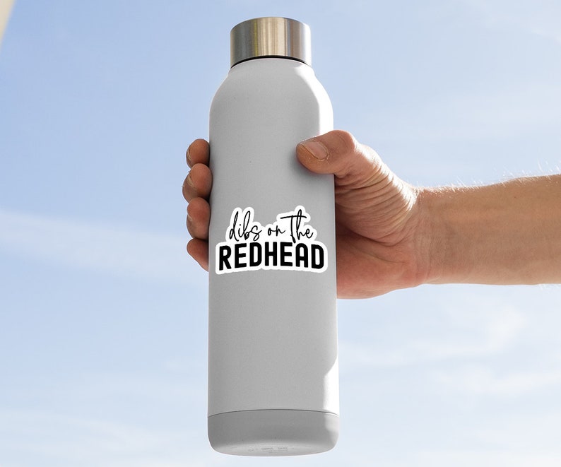 May include: A white stainless steel water bottle with a black sticker that says "dibs on the redhead".