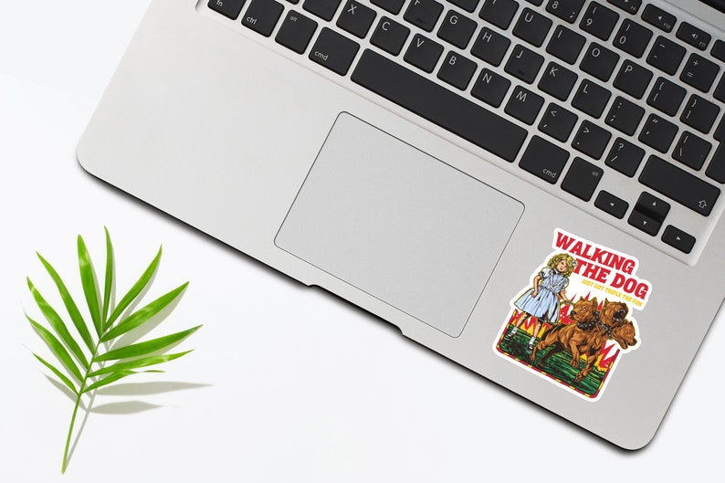 May include: A sticker featuring a cartoon illustration of a girl walking three dogs. The sticker is on a silver laptop. The sticker has the text "Walking the Dog" and "Don't get people on fire".
