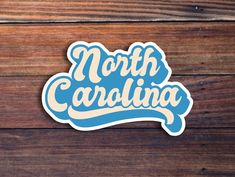 K&ouml;nnte beinhalten: Ein blauer und wei&szlig;er Aufkleber mit dem Text "North Carolina" in einem Retro-Schriftart-Stil.