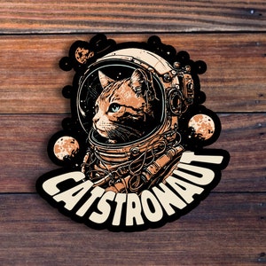 May include: A black and white illustration of a cat wearing an astronaut helmet with the text "Catstronaut" in a white font.