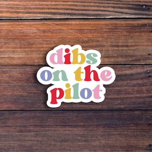 May include: A colorful sticker with the text "dibs on the pilot" in a playful font.