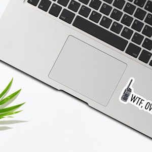 May include: A laptop computer with a sticker of a walkie-talkie and the text "WTF, OVER." on the bottom right corner of the trackpad.
