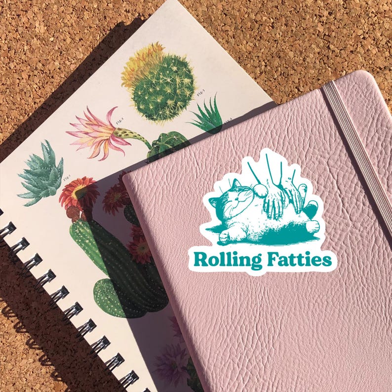 May include: A teal green sticker with a cartoon illustration of a cat being petted by two hands. The text "Rolling Fatties" is printed below the cat.