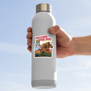 May include: A white water bottle with a sticker of a girl walking a three-headed dog. The sticker says "Walking the Dog, Don't Get Snapped by the Pup."