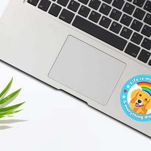 Puede incluir: Una pegatina azul y blanca con un arco&iacute;ris y un cachorro golden retriever. La pegatina dice "La vida no tiene sentido y todo muere".