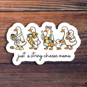 May include: A sticker featuring a cartoon illustration of a family of ducks. The ducks are depicted in various scenarios, such as holding coffee, groceries, and string cheese. The text "just a string cheese mama" is written in cursive below the ducks.