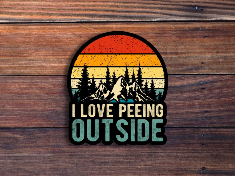 May include: A vintage-style sticker featuring a sunset scene with mountains. The text "I LOVE PEEING OUTSIDE" is written in a bold font.