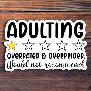 May include: A white sticker with black text that reads "ADULTING" above the phrase "OVERRATED & OVERPRICED. Would not recommend." A yellow star is next to the word "ADULTING" and four outlined stars are below it.
