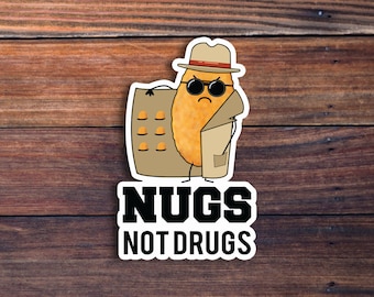 May include: A cartoon chicken nugget wearing a detective hat and sunglasses, holding a box of chicken nuggets. The text "NUGS NOT DRUGS" is below the image.