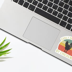 May include: A sticker with a retro design featuring a chicken and the text "Easily Distracted by Chickens".