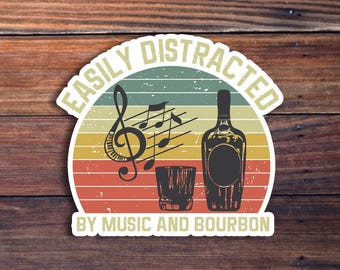 May include: A vintage-style sticker with the text "Easily Distracted by Music and Bourbon". The sticker features a retro design with a musical note, a glass of bourbon, and a bottle of bourbon.