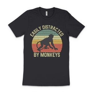 May include: Black t-shirt with a vintage-style graphic of a monkey and the text "Easily Distracted By Monkeys".