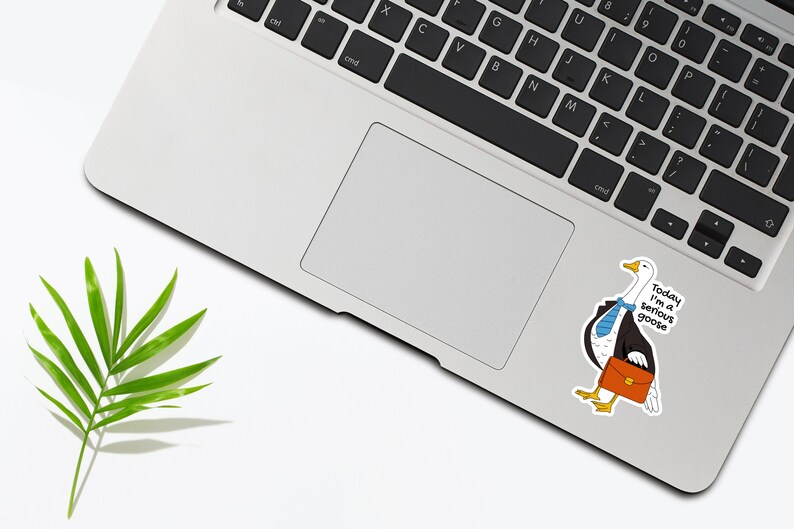 May include: A white laptop computer with a black keyboard and a trackpad. A sticker of a goose wearing a suit and tie is on the laptop. The sticker says "Today I'm a serious goose".